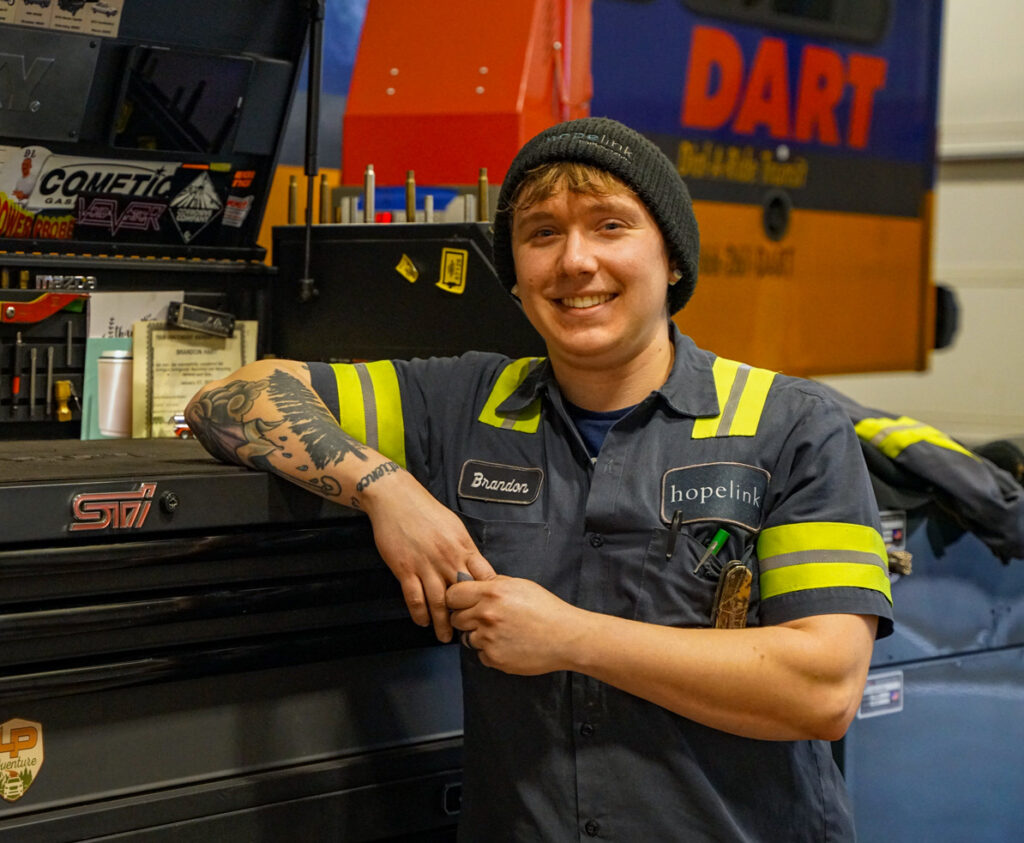 Automotive service technician, Brandon poses Infront of a mechanics workbench. 