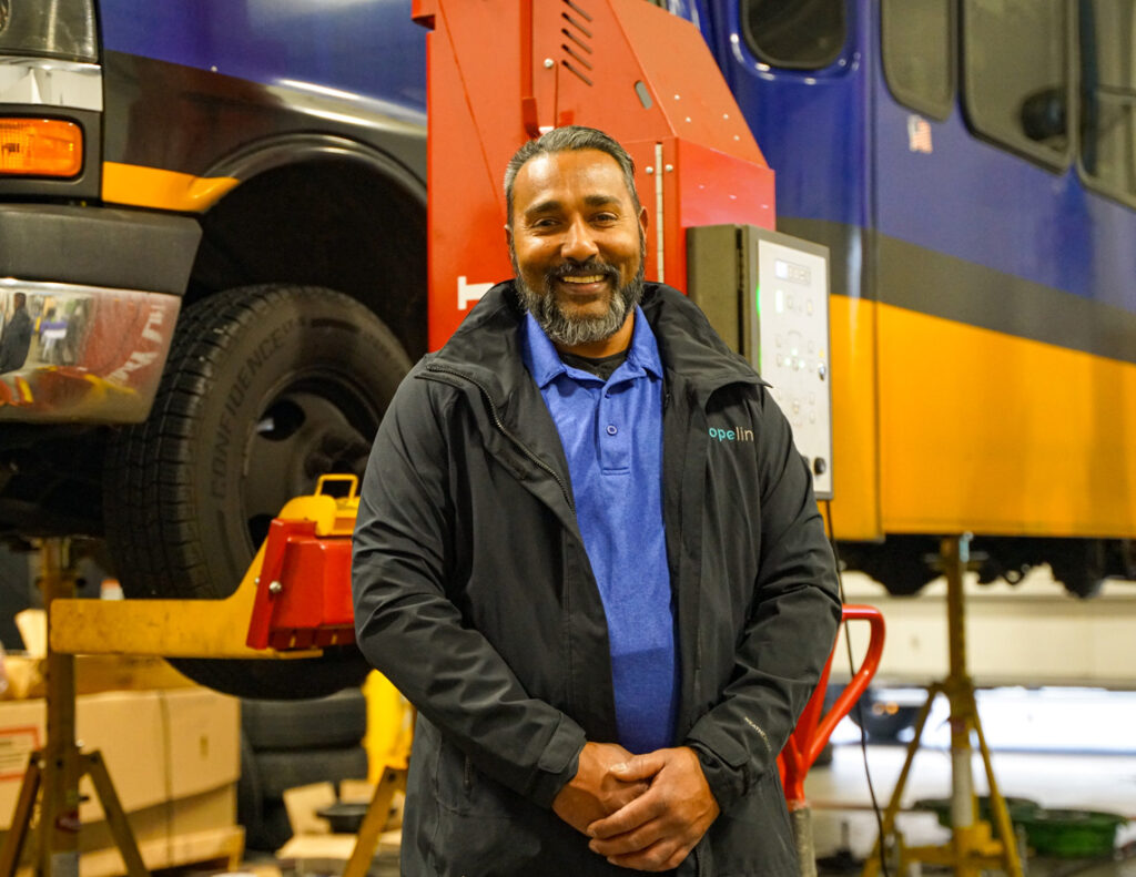 Fleet maintenance shop manager, Shawn poses in front of a DART bus on a service lift.