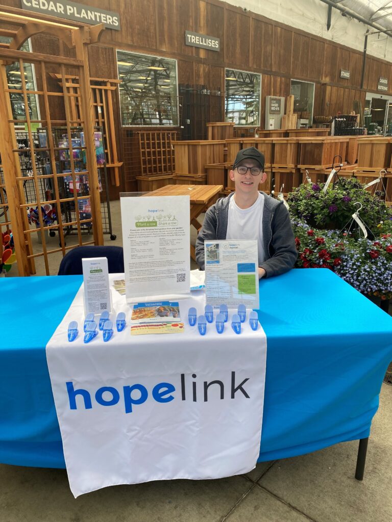 Better Together: How Corporate Partnerships Impact Hopelink's Work 3 Levi O'Tool at Sky Nursey with a Hopelink table